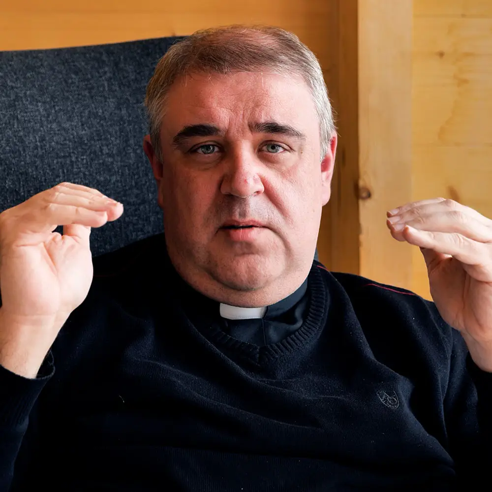 Ksiądz w koloratce mówi do kamery i gestykuluje; przesłanie: żyjemy po to, aby poznać Boga.