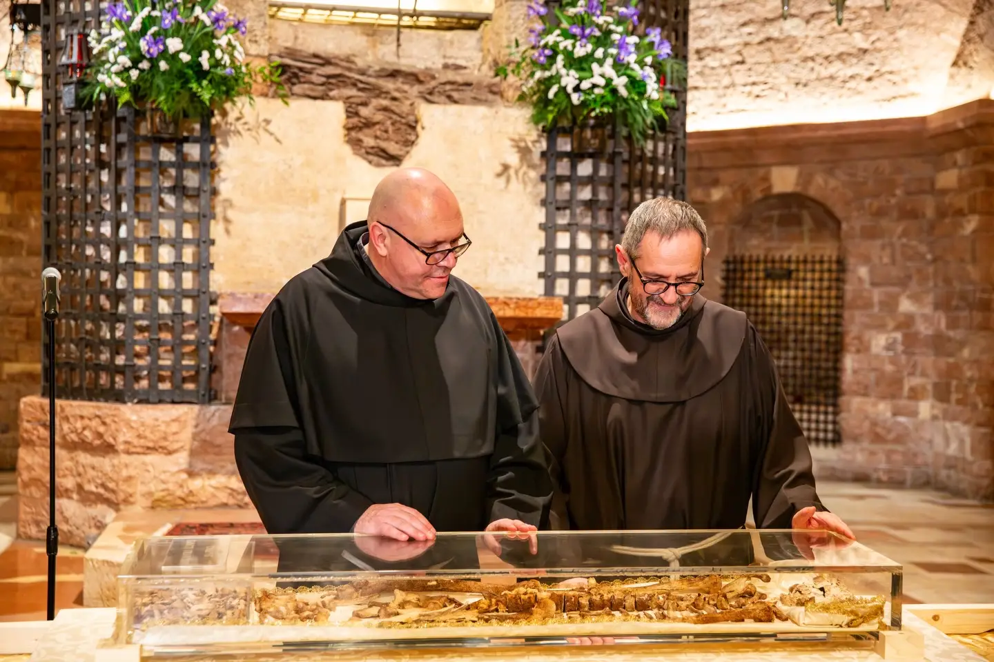 Dwaj franciszkanie przy szklanej trumnie z relikwiami św. Franciszka w bazylice w Asyżu.