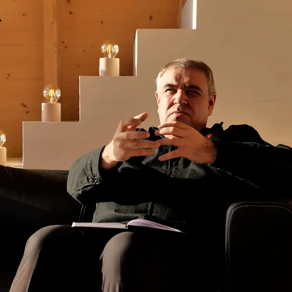 Ks. Robert Woźniak siedzi na kanapie i gestykuluje, omawiając Trójcę Świętą i liturgię jako dzieło Trójcy.