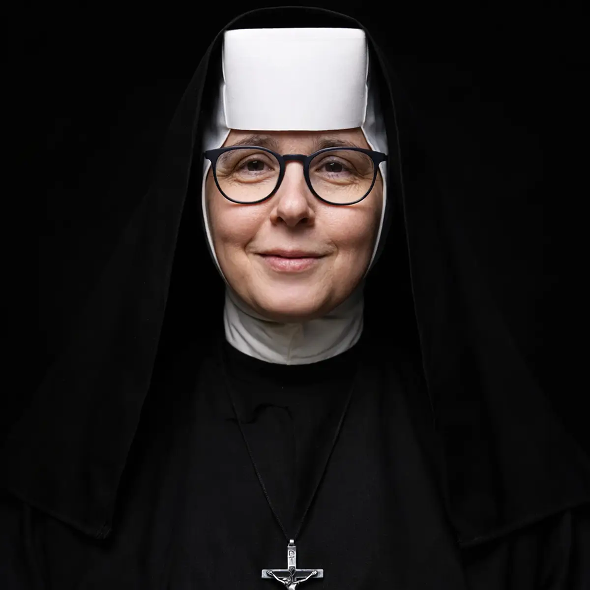 Portret zakonnicy w habicie i okularach na czarnym tle